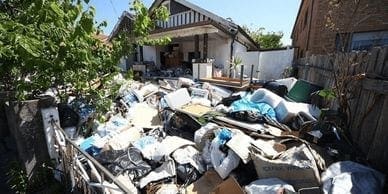 A pile of trash in front of a house waiting for junk removal service.