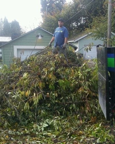A man standing in front of a pile of leaves for trash removal.