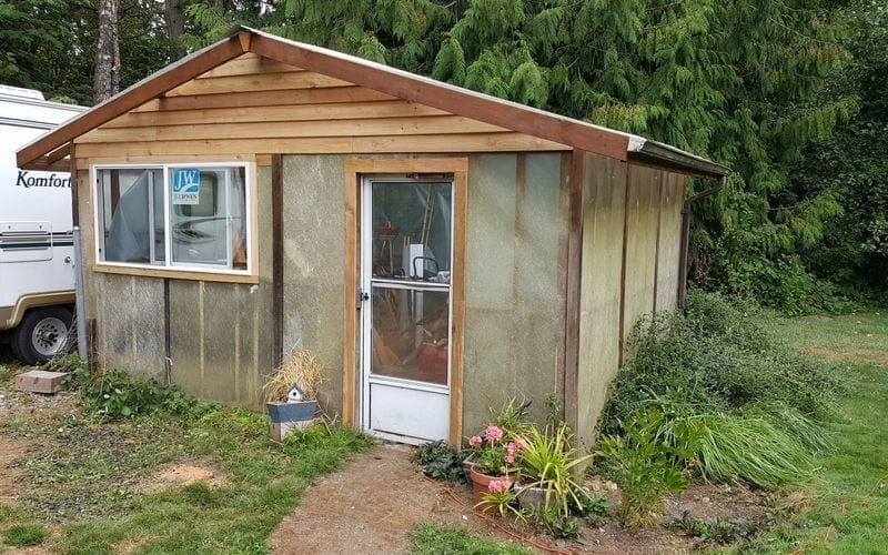 A small shed with a rv parked next to it in need of trash removal services.