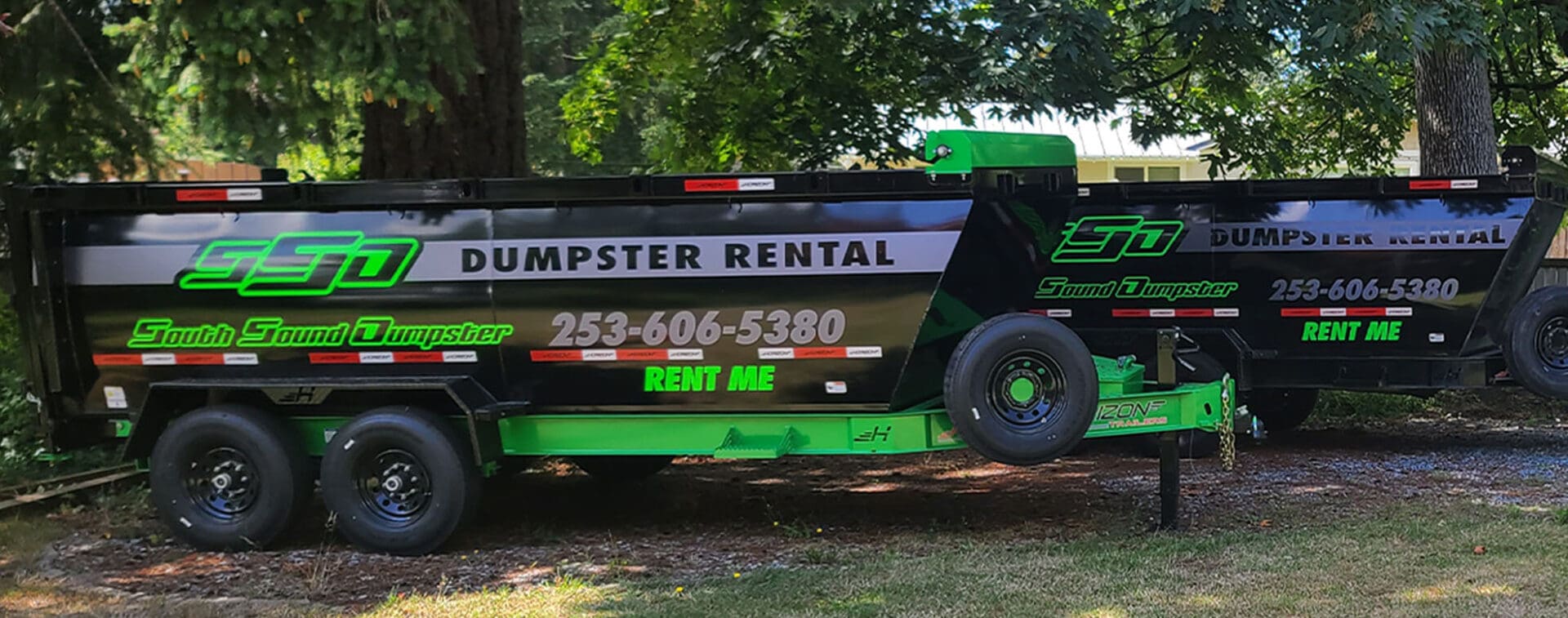 A dumpster rental truck parked in the grass.