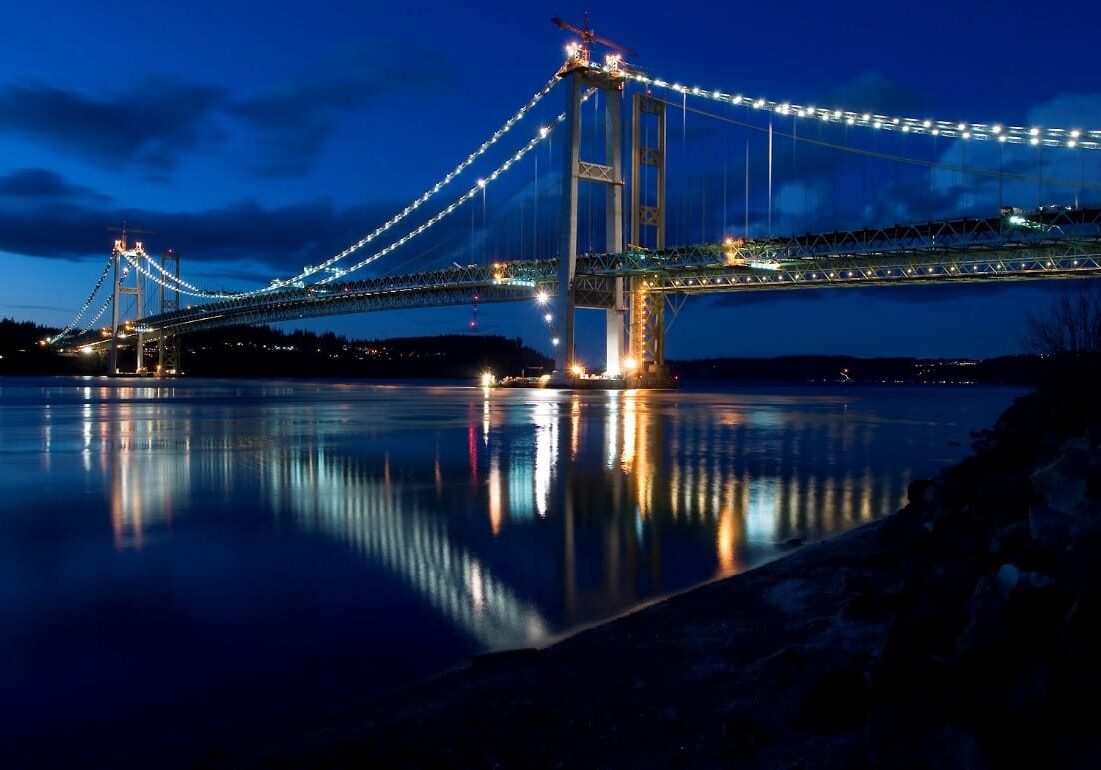 A bridge is lit up at night over a body of water, with no connection to Junk & Trash Removal Services.